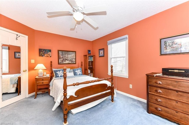 bedroom with ceiling fan, light colored carpet, and a textured ceiling