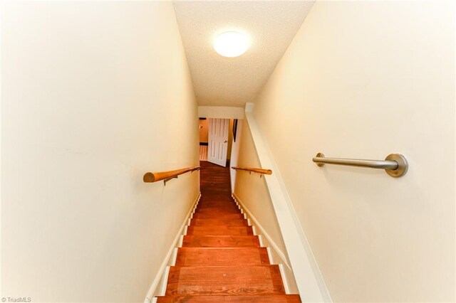 stairway featuring wood-type flooring and a textured ceiling