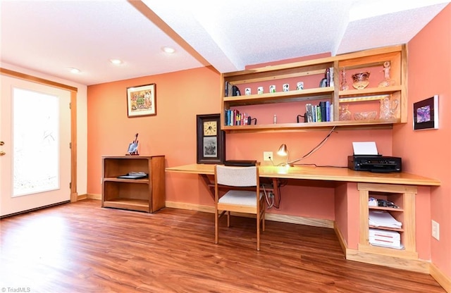 home office with wood-type flooring and built in desk