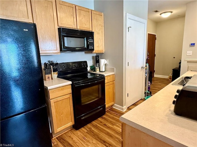 411 Washington St Unit 204, Greensboro, NC 27401 - kitchen featuring black appliances, light wood-style flooring, light brown cabinets, light countertops, and baseboards