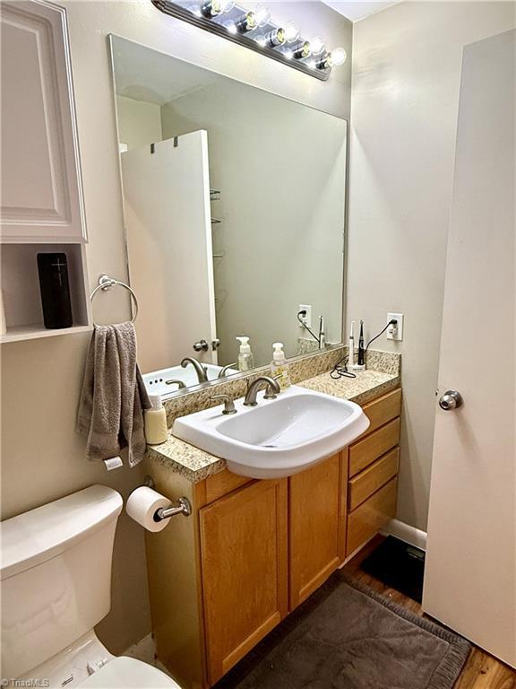 411 Washington St Unit 204, Greensboro, NC 27401 - bathroom featuring vanity, toilet, and wood finished floors