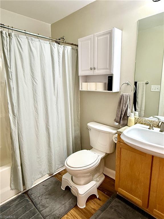 411 Washington St Unit 204, Greensboro, NC 27401 - full bath featuring toilet, wood finished floors, vanity, and shower / tub combo