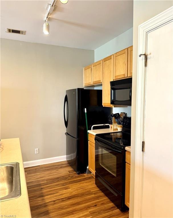 411 Washington St Unit 204, Greensboro, NC 27401 - kitchen featuring black appliances, track lighting, wood finished floors, a sink, and light countertops