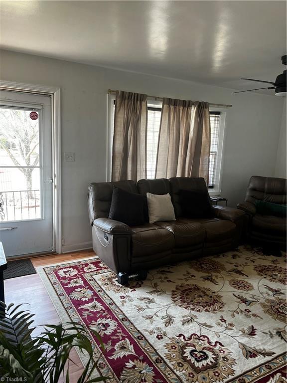 living area featuring a ceiling fan, a healthy amount of sunlight, and wood finished floors