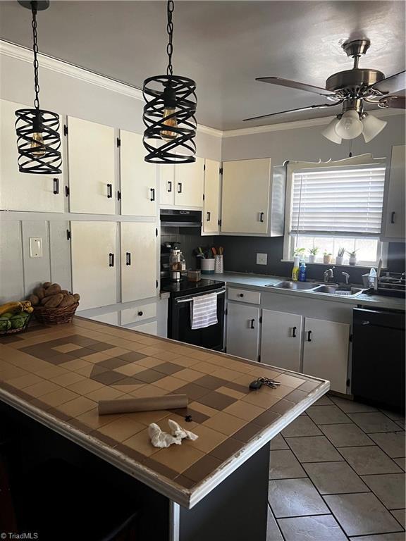 kitchen with tile countertops, hanging light fixtures, ornamental molding, white cabinets, and black appliances