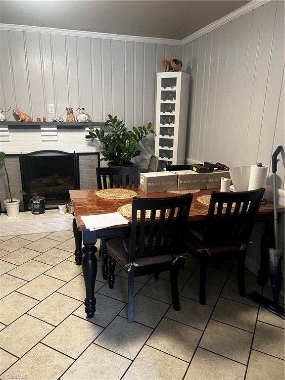 dining room featuring ornamental molding, a brick fireplace, and light tile patterned floors