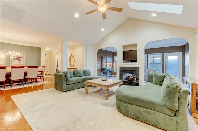 living room featuring ceiling fan with notable chandelier, a multi sided fireplace, high vaulted ceiling, and light wood-type flooring