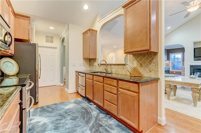 kitchen featuring vaulted ceiling, appliances with stainless steel finishes, light wood-type flooring, ceiling fan, and sink