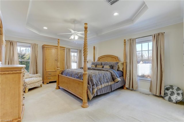 bedroom featuring light carpet, crown molding, ceiling fan, multiple windows, and a tray ceiling