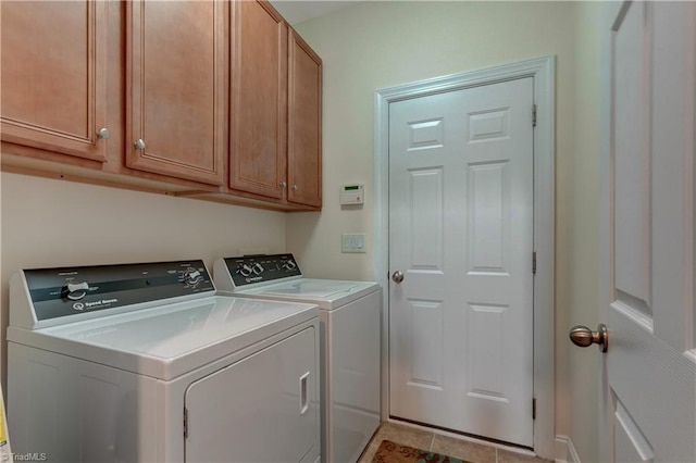 clothes washing area featuring washer and clothes dryer, light tile patterned floors, and cabinets