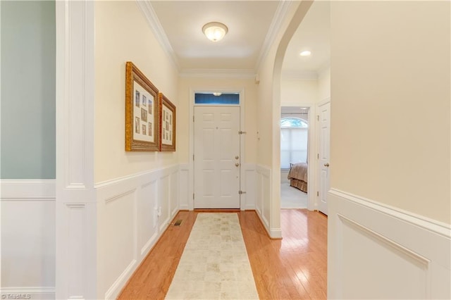 doorway with ornamental molding and light hardwood / wood-style flooring