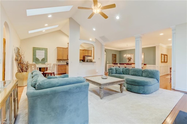 living room with ceiling fan with notable chandelier, high vaulted ceiling, ornamental molding, and light hardwood / wood-style floors