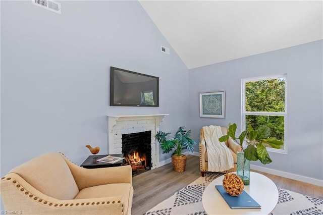 living room featuring light hardwood / wood-style flooring, high vaulted ceiling, and a fireplace