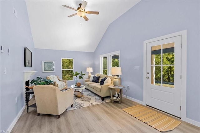 living room featuring light hardwood / wood-style flooring, high vaulted ceiling, and ceiling fan