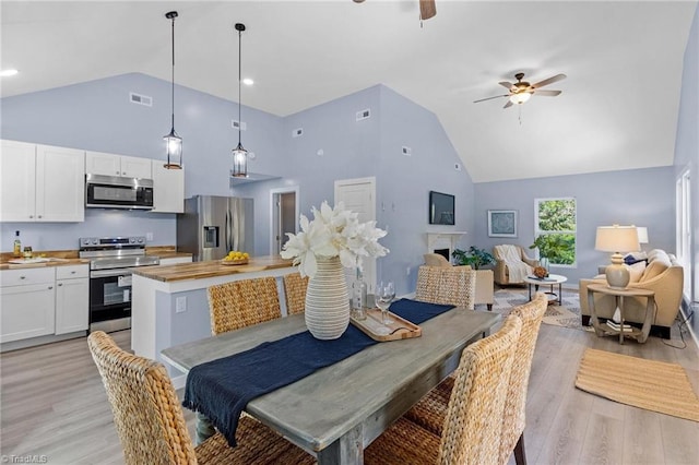 dining area with ceiling fan, high vaulted ceiling, and light hardwood / wood-style flooring