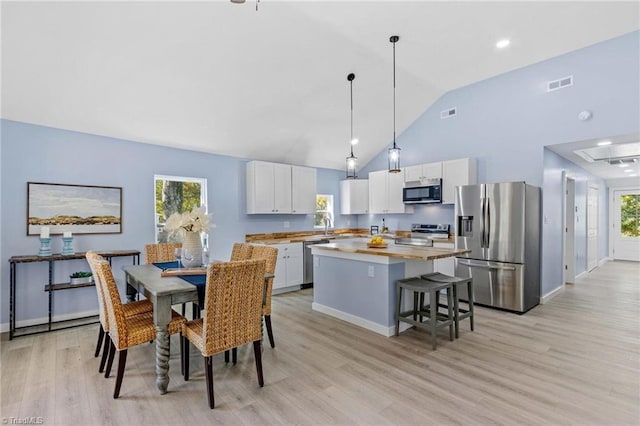 dining room with sink, light hardwood / wood-style flooring, high vaulted ceiling, and a wealth of natural light