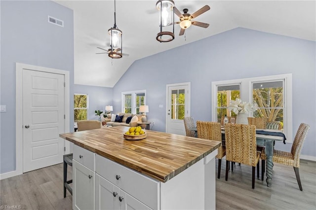 kitchen with white cabinets, decorative light fixtures, light wood-type flooring, and plenty of natural light