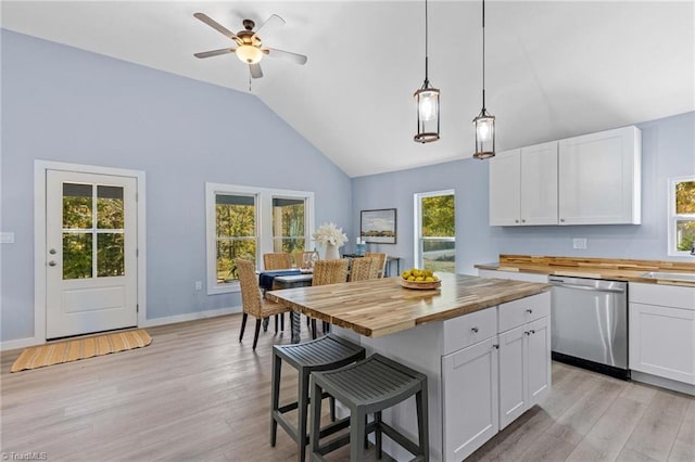 kitchen featuring wooden counters, stainless steel dishwasher, white cabinets, and a healthy amount of sunlight