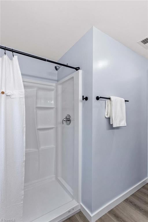 bathroom with a shower with shower curtain and wood-type flooring