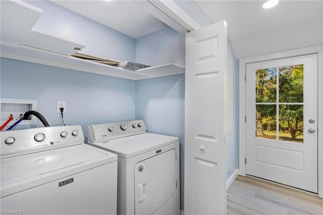 clothes washing area with independent washer and dryer and light hardwood / wood-style flooring