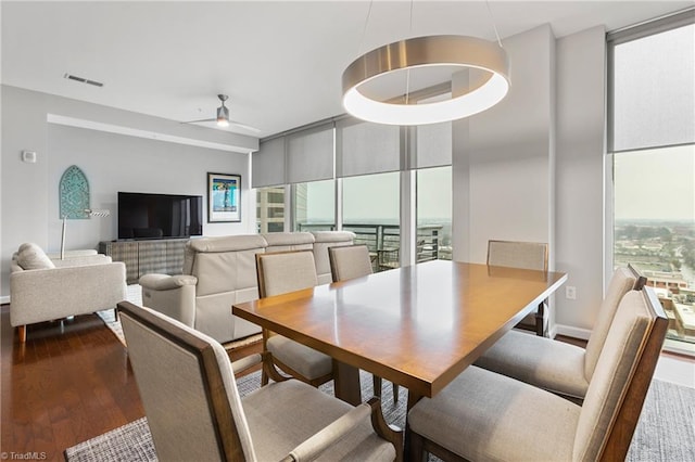 dining room featuring dark wood-type flooring, ceiling fan, and expansive windows