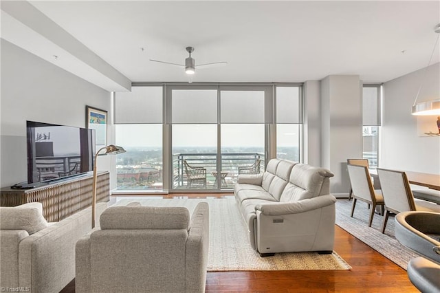 living room featuring a healthy amount of sunlight, ceiling fan, hardwood / wood-style floors, and a wall of windows