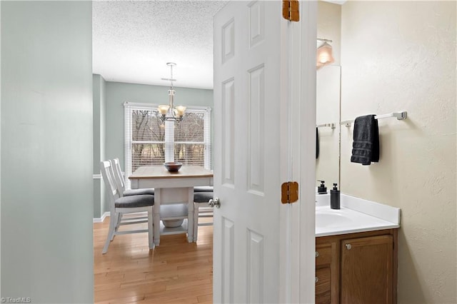 bathroom with an inviting chandelier, vanity, hardwood / wood-style floors, and a textured ceiling