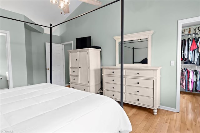 bedroom featuring vaulted ceiling, a spacious closet, light hardwood / wood-style floors, and a closet