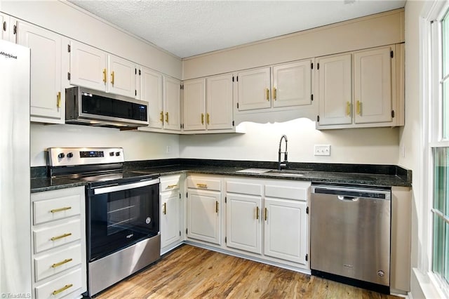 3985 Valley Ct Unit B, Winston-Salem, NC 27106 - kitchen with stainless steel appliances, a sink, light wood finished floors, white cabinetry, and plenty of natural light