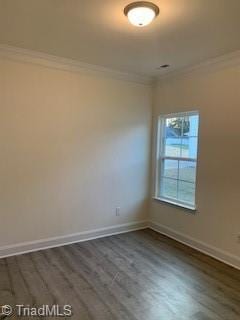 empty room featuring dark wood-style floors, baseboards, and crown molding