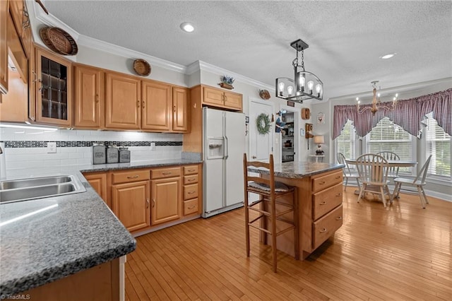 kitchen with white refrigerator with ice dispenser, a chandelier, a textured ceiling, ornamental molding, and tasteful backsplash