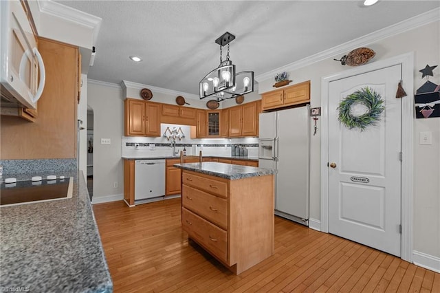 kitchen featuring white appliances, a kitchen island, light wood-style flooring, ornamental molding, and a chandelier