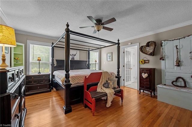 bedroom featuring ornamental molding, light wood-type flooring, a textured ceiling, and a ceiling fan