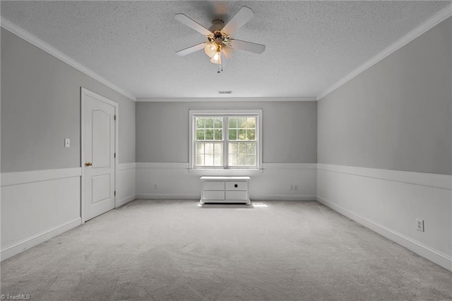 carpeted spare room with a textured ceiling, ceiling fan, and crown molding
