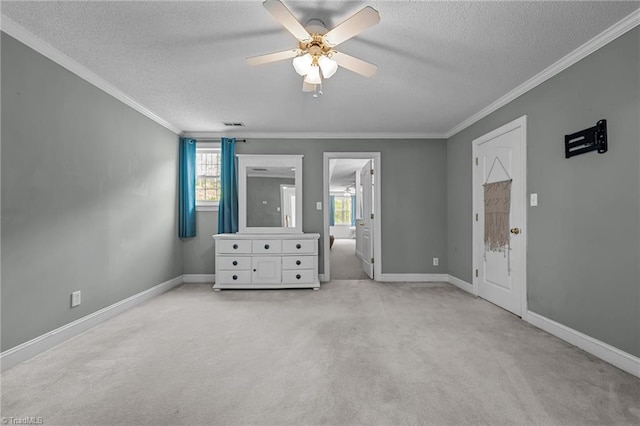 unfurnished bedroom featuring a textured ceiling, light colored carpet, ornamental molding, baseboards, and a ceiling fan