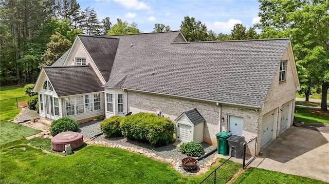 back of property with a sunroom, a shingled roof, an attached garage, and brick siding