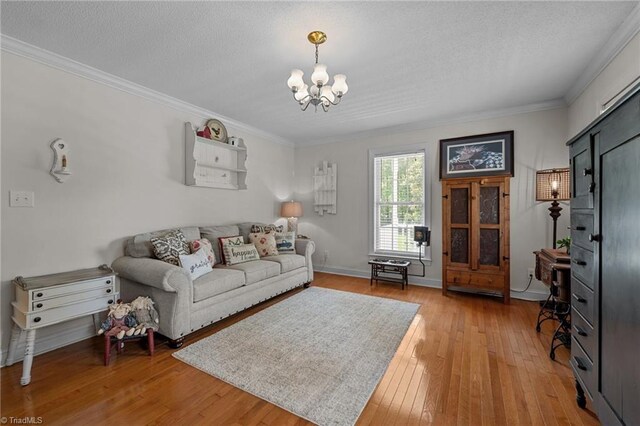 living area featuring a chandelier, crown molding, light wood-style flooring, a textured ceiling, and baseboards