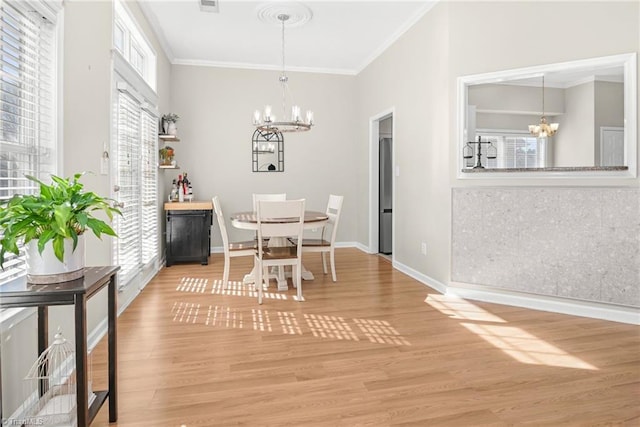 dining room with a chandelier, crown molding, and light wood-style floors