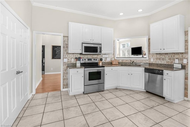 kitchen with backsplash, ornamental molding, white cabinets, stainless steel appliances, and a sink