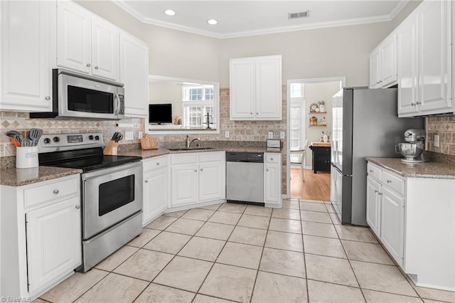 kitchen with light tile patterned floors, white cabinets, appliances with stainless steel finishes, and ornamental molding