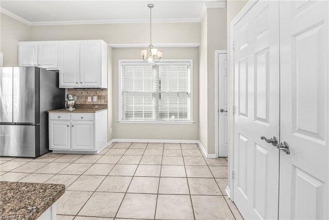 kitchen featuring decorative backsplash, light tile patterned floors, freestanding refrigerator, and ornamental molding