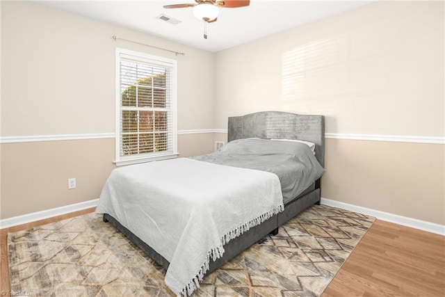 bedroom with visible vents, baseboards, wood finished floors, and a ceiling fan