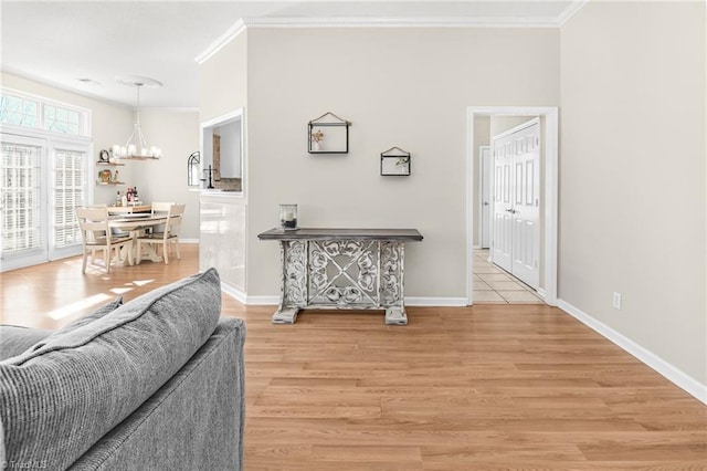 living area featuring a chandelier, crown molding, light wood-type flooring, and baseboards