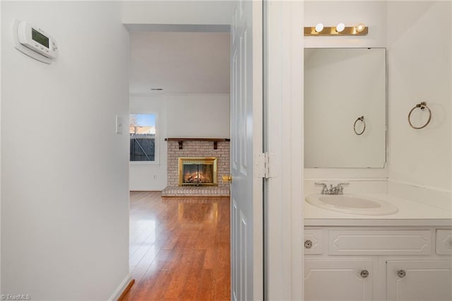 bathroom featuring vanity, a brick fireplace, and hardwood / wood-style flooring