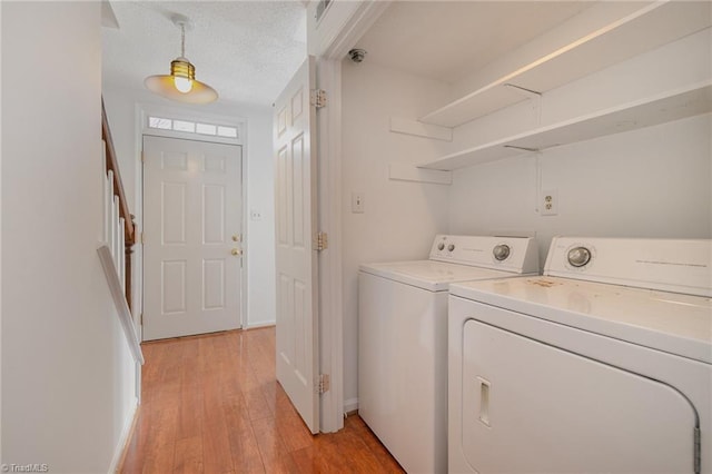 laundry area featuring light wood-type flooring, a textured ceiling, and independent washer and dryer