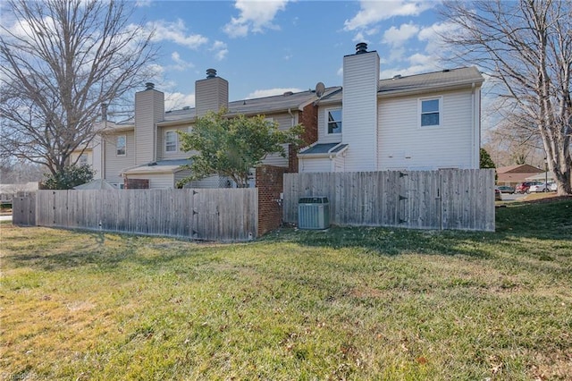 rear view of property featuring a lawn and central air condition unit