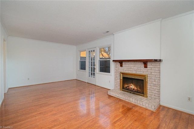 unfurnished living room featuring crown molding, a brick fireplace, and light hardwood / wood-style floors