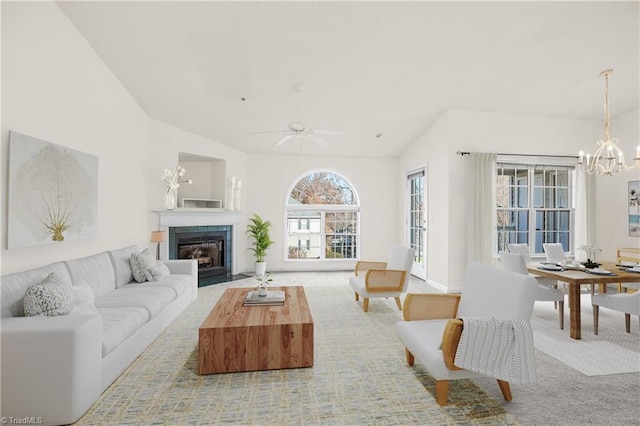 living room featuring ceiling fan with notable chandelier, light colored carpet, and vaulted ceiling