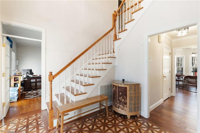 staircase featuring baseboards, wood finished floors, visible vents, and ornamental molding