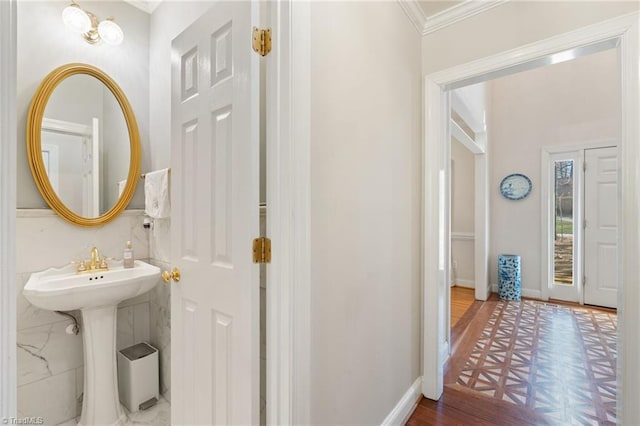 bathroom featuring a sink, wood finished floors, baseboards, and ornamental molding